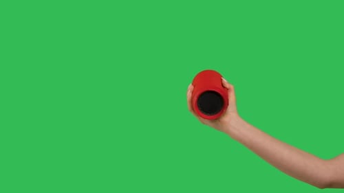 Foto recortada da mão feminina segurando um alto-falante Bluetooth vermelho sem fio na tela verde Chroma Key