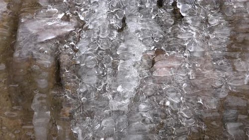 Wasser- und Luftblasen fließen durch das glasige transparente Eis
