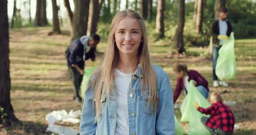 Woman Posing on Camera Near Volunteers from Eco Team which with Plastic Bags Trash in the Park