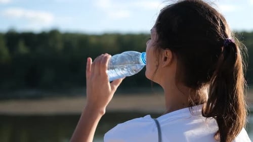 Fitness Girl Drinks From a Bottle During a Break in Outdoor Workout. Close Up Portrait of Active