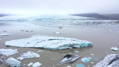 Flying Over Floating Icebergs in Fjallsarlon Glacial Lagoon, Iceland. Aerial View of Melting Ice Cap