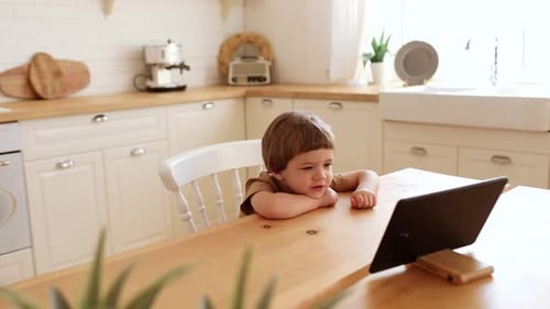 Boy Watching Tablet at Kitchen Table During Daytime