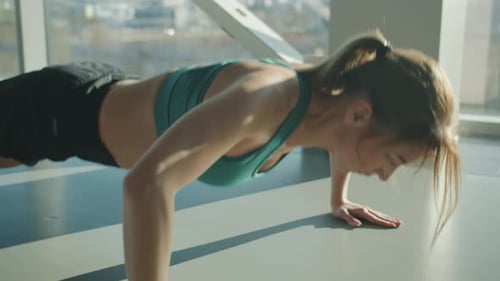 Portrait of Beautiful Young Sportswoman Doing Pushups Indoors in Modern Gym