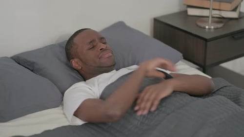 Hombre africano molesto acostado en la cama llorando