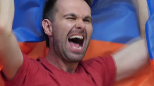 Man Cheering While Holding a Flag