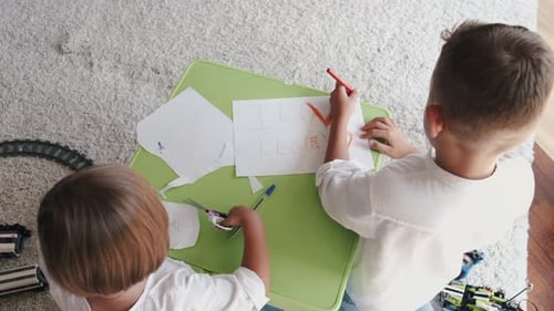 Two Kids Drawing with Colorful Pencils Together at Home
