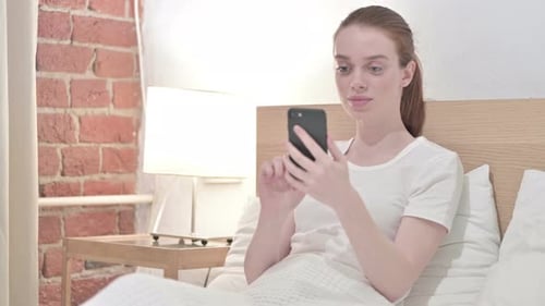 Woman Using Mobile Phone in Bed