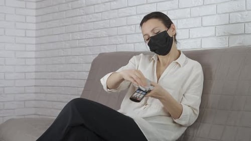 Woman Cleans TV Remote on Sofa