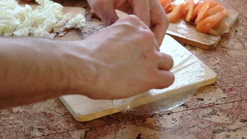 Male Hands Wrap Cutlet and Vegetables Tomato and Chinese Cabbage in Rice Paper.