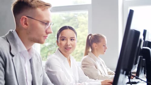 Diverse team of young professionals is working in the phone support office.
