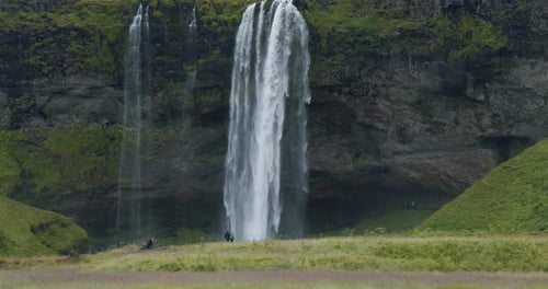 Beautiful Seljalandsfoss Waterfall Iceland From Distance with Unrecognized Tourist Walking Around