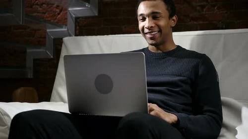 Man Video Calling Using Laptop on White Couch
