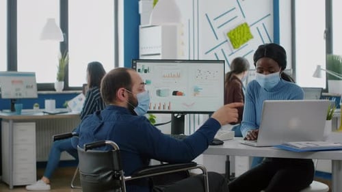 Divers collègues portant des masques faciaux travaillent ensemble dans un nouveau lieu de travail normal