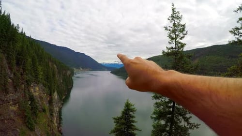Arm Points to Scenic Lake Surrounded by Mountains