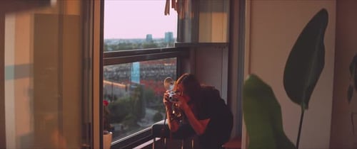 Woman photographer taking a picture of a plant on the balcony