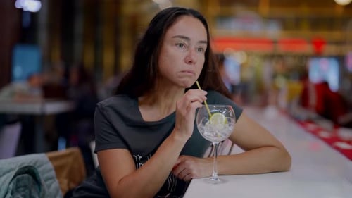 Lonely Brunette Woman is Sipping Alcohol Cocktail in Bar of Hotel Waiting Someone