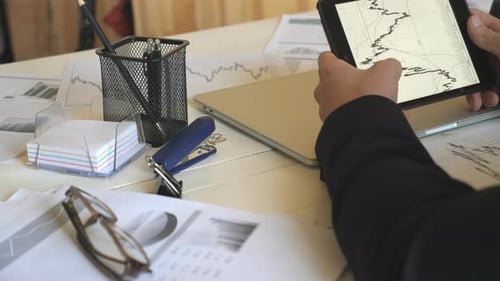 Businessman Reviews Charts on Tablet in Office