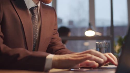 Young Caucasian Businessman Typing on Laptop while Working Late in Office