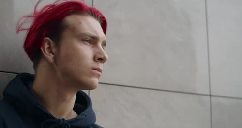 Nahaufnahme eines jungen depressiven Hipster-Mannes, der zur Seite schaut. Porträt eines Millennial Guy mit Rotfärbung
