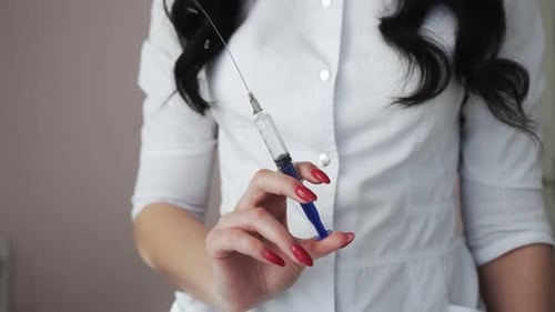 Ärztin hält Nadelspritze und spritzt Medizin aus der Spritze