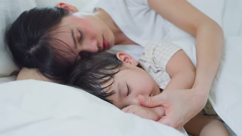 Mother and Child Sleeping Peacefully in White Bed