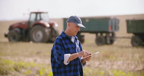 Farmer Using Digital Tablet While Examining Field