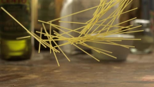 Spaghetti Falling on a Rustic Wooden Surface