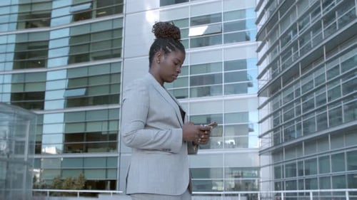 Focused Young Business Lady Standing Among City Office Buildings