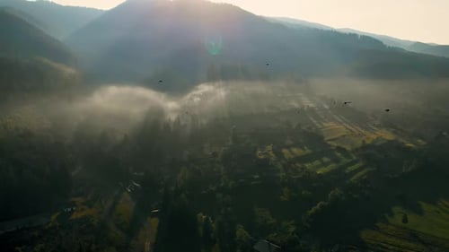 Luftaufnahme des Sonnenaufgangs über einem nebligen Dorf in den Bergen.