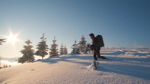 Man Backpacker Hiking Snowy Mountain Hillside on Cold Winter Morning