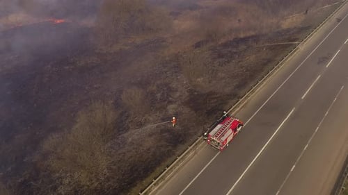 Firemen Extinguish Burning Field Near Highway