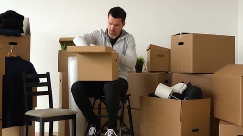 Young Man Packing Belongings Into Boxes