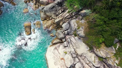 Beautiful cliffs naturally caved by ocean waves splashing and foaming on rocky coastline of tropical