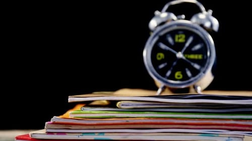 Alarm Clock on Stack of Colorful Notebooks