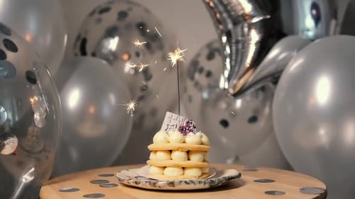 Sparkler Burns Atop Small Birthday Cake with Balloons