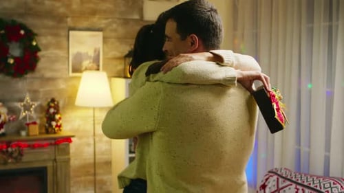 Loving Couple Share Christmas Embrace With Gift
