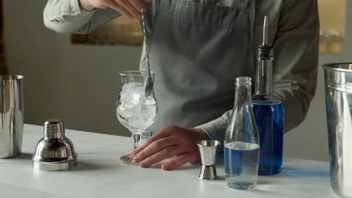 Professional Man Bartender Stirring Ice in the Glass on the Bar Counter