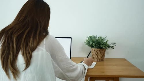 Woman Works at Home on Laptop, Taking Notes