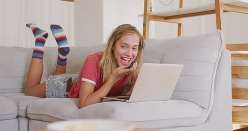 Happy Woman Chatting on Phone While Using Laptop