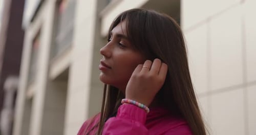 Woman Puts Wireless Headphones in Ears Outdoors