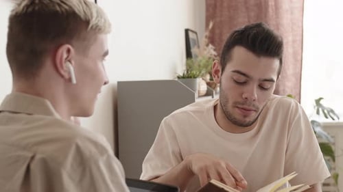 Deux jeunes hommes assis à table et communiquant