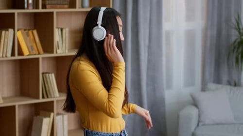 Woman Dancing to Music With Headphones in Living Room