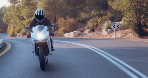 Man riding on a white sports motorcycle in a curvy highway
