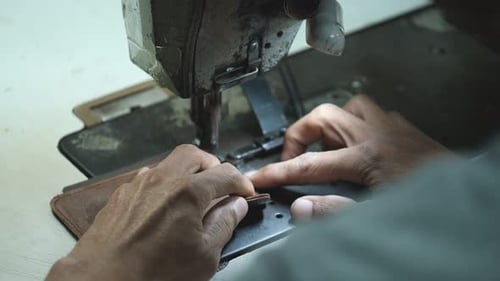 Close-Up Of Tailor Working On Sewing Machine in leather factory background