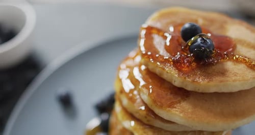 Maple Syrup Pouring onto Stack of Pancakes with Blueberries