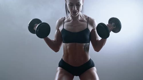 Muscular Woman Doing Bicep Curls with Dumbbells
