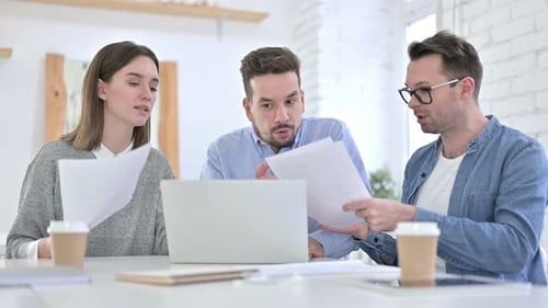 Three Adults Discussing Business at Table With Laptop