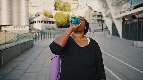 Woman Drinks Water After Exercise in the City