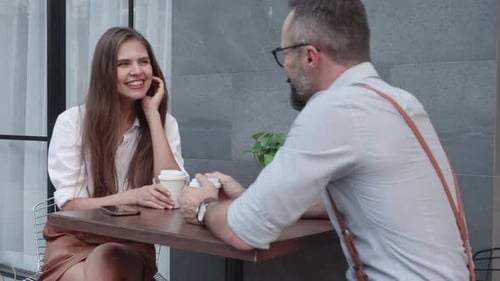 Glückliches junges Paar, das zusammen am Tisch spricht und Kaffee trinkt, Mann und Frau sind Freund.