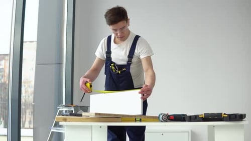 The Carpenter in Protective Glasses Measures the Parts
